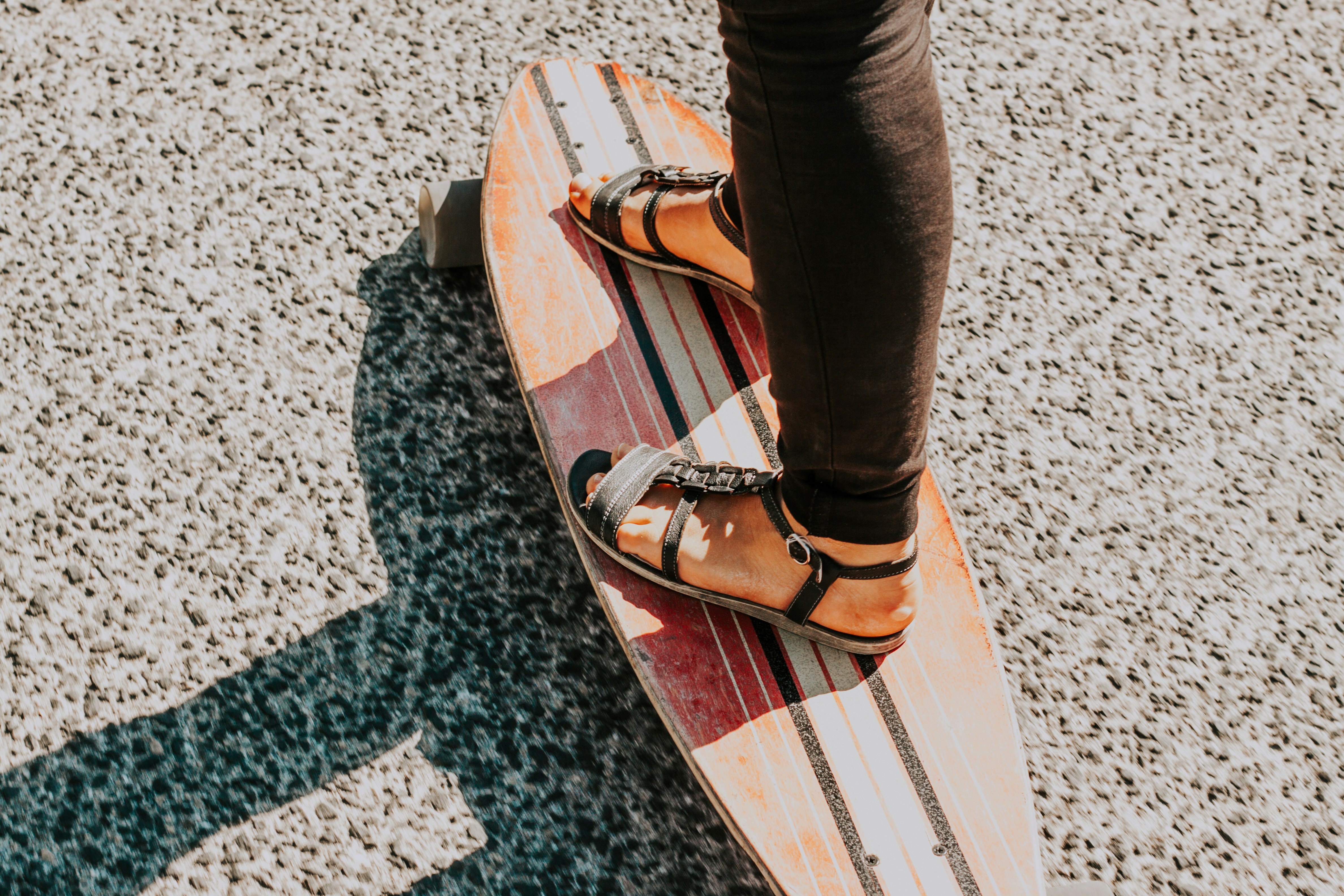 person wearing black sandals on long board